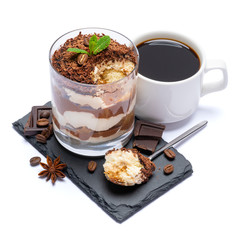 Classic tiramisu dessert in a glass cup and pieces of chocolate on stone cutting board on white background with clipping path