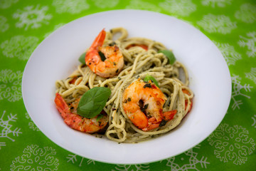 King prawns and pesto sauce with spaghetti on the green background