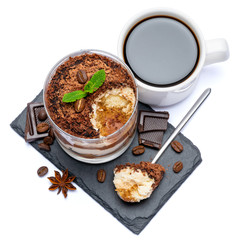 Classic tiramisu dessert in a glass cup and pieces of chocolate on stone cutting board on white background with clipping path