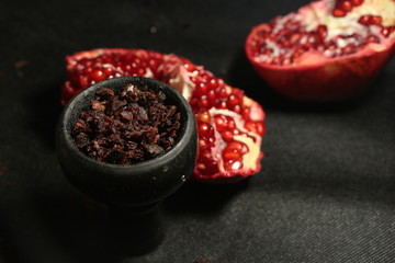 bowl with tobacco for hookah. red pomegranate on a dark background. smoking hooka