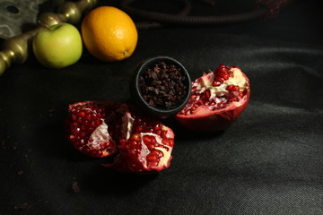 bowl with tobacco for hookah. pomegranate on a black background. smoking hooka
