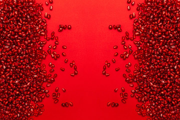 Ripe pomegranate seeds on a red background. Horizontal orientation. The view from the top. The...