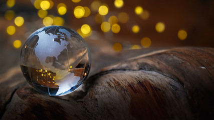 Glass earthball on a wooden grown with golden lights in Background - christmas or new year 2023