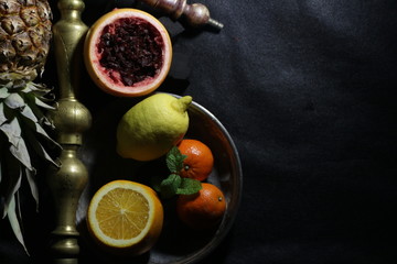 bowl with tobacco for hookah. fruits on a black background. smoking nargile