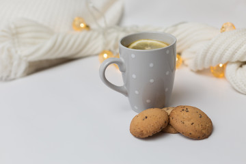 Lemon tea, cookies and tangerines on a white background with a knitted scarf with flower garlands