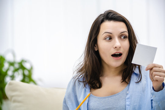 Attractive woman is looking at paper sticket with amusement She wants to win a lottery. Copy space. Close up.