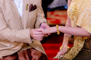 Obraz premium Wedding rings. He Put the Wedding Ring on Her. Close up Groom Put the Ring on bride. thai wedding ceremony and thai wedding decoration.