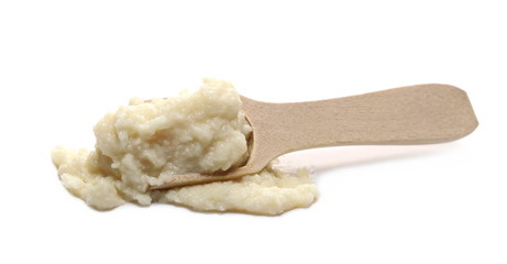 Horseradish sauce in wooden spoon, isolated on white background