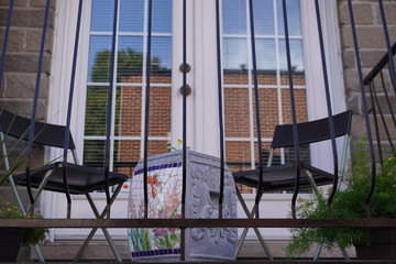 A beautiful disposition of objects on a balcony. In the back, you can see the reflection of the building in the window.