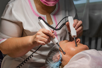 A cosmetic procedure with microcurrent injections in a beauty salon is performed for an aged woman. Improving skin turgor, rejuvenation and healing.