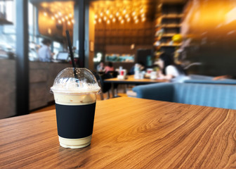 Iced Latte cup on wooden table in Coffee shop blur background.