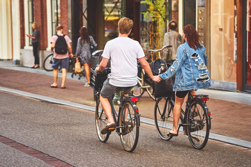 Young dutch couple on the bikes holding hands - obrazy, fototapety, plakaty