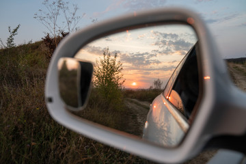 Beautiful sunset is displayed in the side mirror of the car