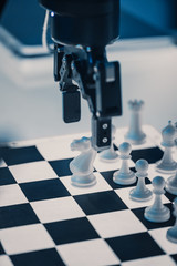 Close Up Vertical Shot of Artificial Intelligence Operating a Futuristic Robotic Arm in a Game of Chess Against a Human. Robot Moves a Pawn. They are in a High Tech Modern Research Laboratory.