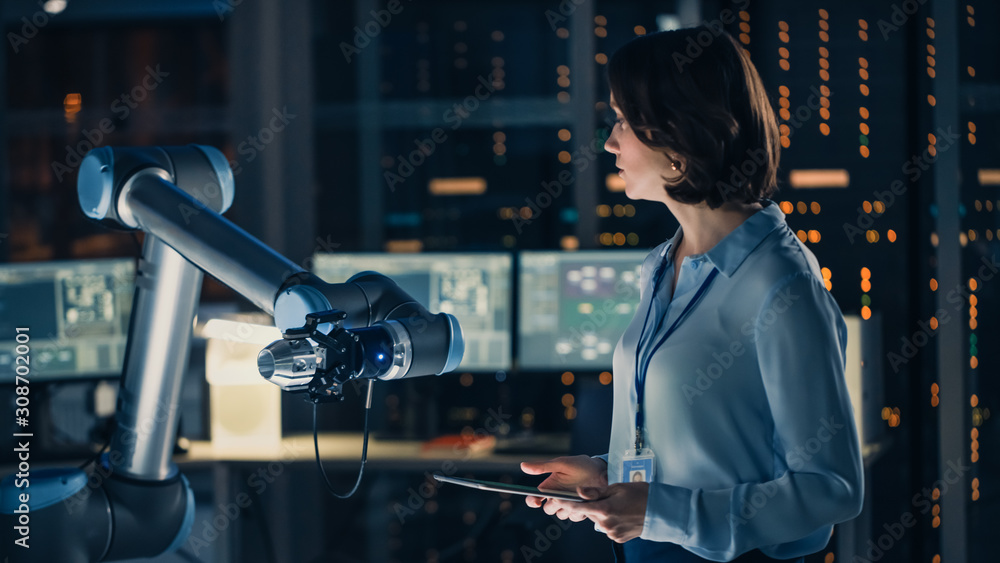 Aufkleber female engineer with tablet computer analyse how a futuristic robotic arm works and moves a metal ob