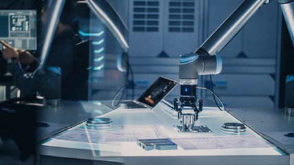 Futuristic Artificial Intelligence Robotic Arm Operates and Moves a Metal Object, Picks It Up or...