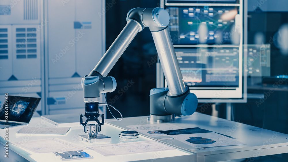 Poster Futuristic Artificial Intelligence Robotic Arm Operates and Moves a Metal Object, Picks It Up and Puts it Down. Scene is Taken in a High Tech Research Laboratory with Modern Equipment.