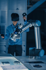 Vertical Shot of Professional Development Engineer in Blue Shirt Controlling Futuristic Robotic Arm with Virtual Reality Headset and Joysticks in a High Tech Research Laboratory with Modern Equipment © Gorodenkoff
