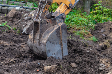Bucket of excavator at work, construction machinery. Detail.