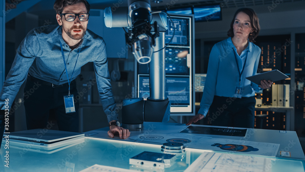 Aufkleber Futuristic Robotic Arm Moving and Placing a Metal Object. Senior Engineer Talks Through This Advanced Process. They are in a High Tech Research Laboratory with Modern Equipment.