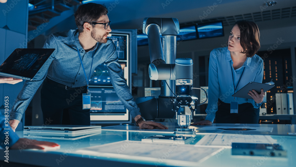 Poster diverse team of engineers with laptop and a tablet analyse and discuss how a futuristic robotic arm 