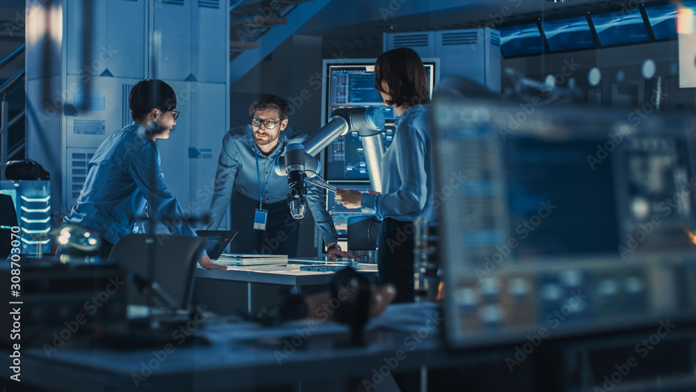 Poster Diverse Team of Engineers with Laptop and a Tablet Analyse and Discuss How a Futuristic Robotic Arm Works and Moves a Metal Object. They are in a High Tech Research Laboratory with Modern Equipment.
