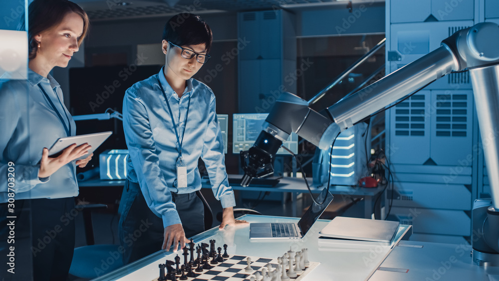 Poster Two Development Engineers are Discussing and Testing an Artificial Intelligence Interface by Playing Chess with a Futuristic Robotic Arm. They are in a High Tech Modern Research Laboratory.