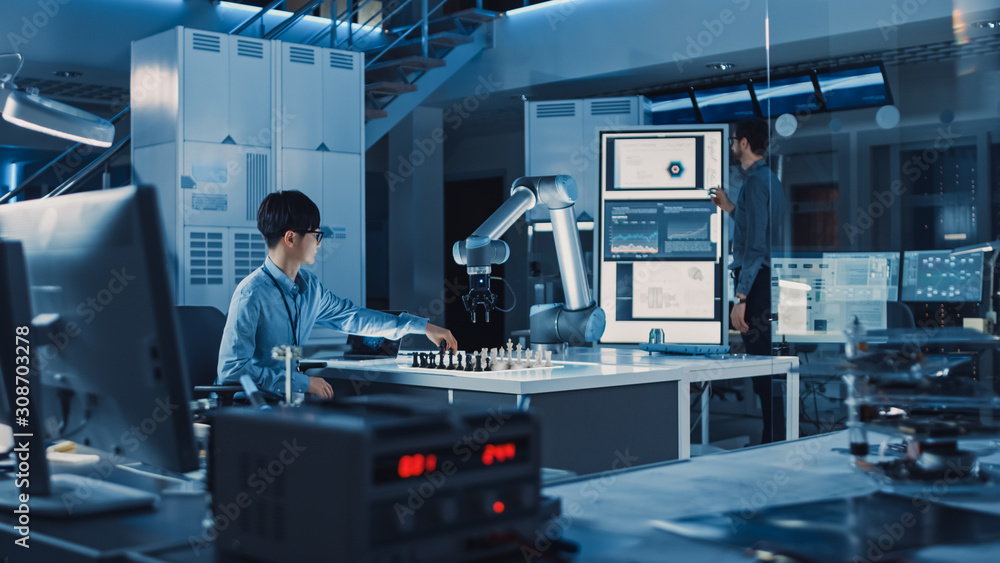 Fototapete Professional Japanese Development Engineer is Testing an Artificial Intelligence Interface by Playing Chess with a Futuristic Robotic Arm. They are in a High Tech Modern Research Laboratory.