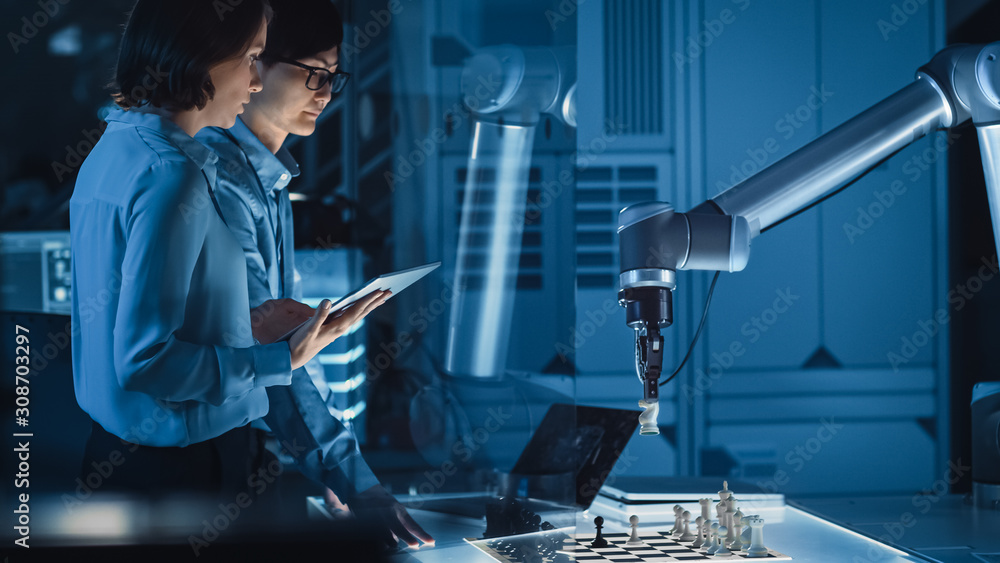 Poster Two Development Engineers are Discussing and Testing an Artificial Intelligence Interface by Playing Chess with a Futuristic Robotic Arm. They are in a High Tech Modern Research Laboratory.