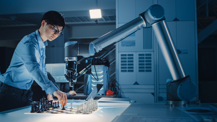 Professional Japanese Development Engineer is Testing an Artificial Intelligence Interface by Playing Chess with a Futuristic Robotic Arm. They are in a High Tech Modern Research Laboratory.