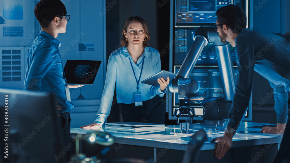 Poster Diverse Team of Engineers with Laptop and a Tablet Analyse and Discuss How a Futuristic Robotic Arm Works and Moves a Metal Object. They are in a High Tech Research Laboratory with Modern Equipment.