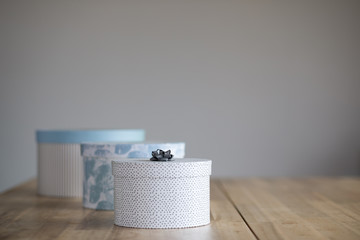 Cardboard round boxes stand in a row on a wooden table with space for text.