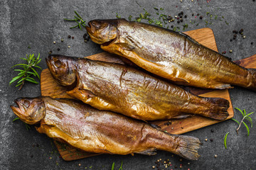 Smoked fish with spices on dark background