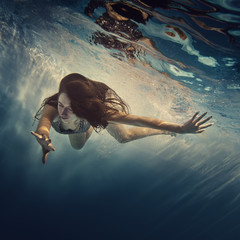 A girl in a brilliant suit swims underwater