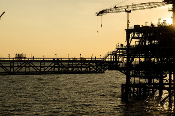 Silhouette of oil production platform during sunset at oil field