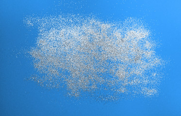 Splash of silver sparkles on classic blue background. Blurry image. Classic blue color of 2020.