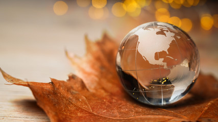 Earth ball globe with canada and usa on a maple leaf in autumn with glowing lights - sustainable,...