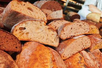 A pile of different wholegrain bread in the store. Cutted loaf. Own bakery. Rustic homemade bakery product.
