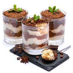 Classic tiramisu dessert in a glass cup on stone serving board and pieces of chocolate on white background with clipping path
