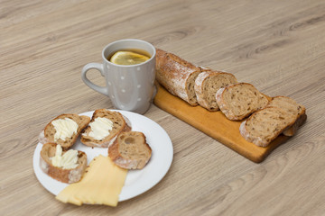 Tea with lemon, sliced bread with cheese and sandwiches