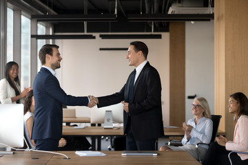 Executive manager shaking hand of successful employee at meeting