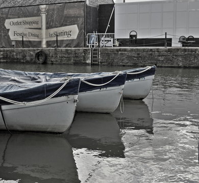 A desaturated image of canal boats tied up on the canal at the Gloucester Quays  in Gloucester, England.