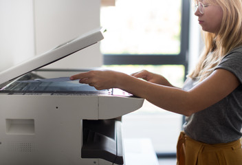Close-up on the hands of a woman doing photocopies in the office. Woman making photocopy using...
