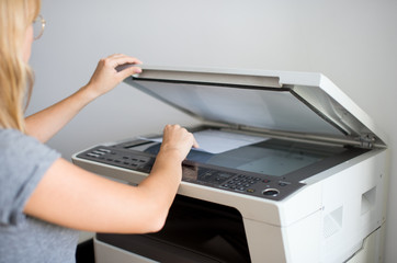 Close-up on the hands of a woman doing photocopies in the office. Woman making photocopy using...