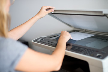 Close-up on the hands of a woman doing photocopies in the office. Woman making photocopy using...