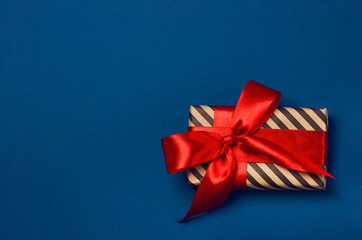 Luxuriously wrapped gift with lush ribbon. Trendy red and blue colors. Copy space. Merry Christmas, St. Valentine's Day, Happy Birthday and other holidays concept.