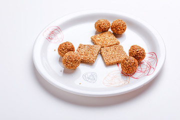 Til Gul OR Sweet Sesame Laddu in Plate with Fikri for Indian festival Makar Sankranti over white background 