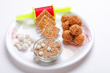 Til Gul OR Sweet Sesame Laddu in Plate with Fikri for Indian festival Makar Sankranti over white background 