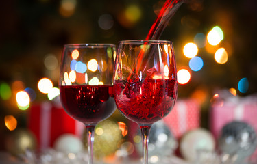 Beautiful splash of red wine and Christmas balls on the background of Christmas lights