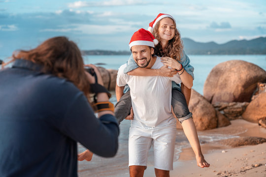 A young couple starred in a video  in Christmas caps on the ocean on a tropical island. Lovers celebrate New Year on the beach and filmed on a professional camera.